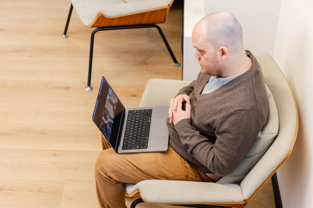 A patient sits with a laptop on his lap during his appointment for virtual medication management in Orlando.
