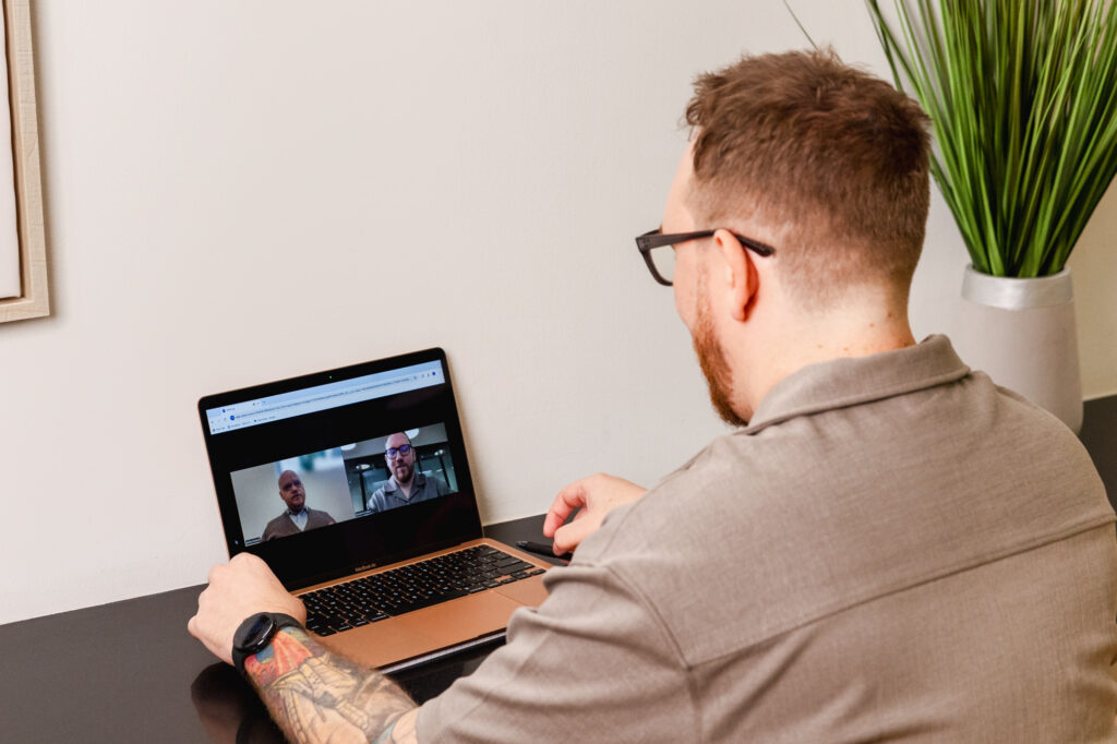 Tranceform Wellness' founder Benjamin Howell sits at a desk with a laptop during virtual psychiatry services in Orlando.